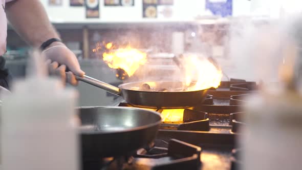 Worker Closes Burning Mussels and Scallops with Frying Pan