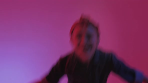 Young Stylish Girl Dancing in the Studio on a Colored Neon Background