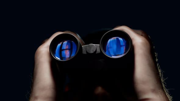 A man looking through binoculars. A guy with field glasses watching a target.