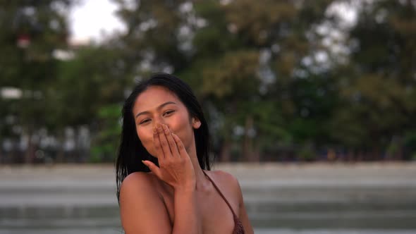 Beautiful Young Woman In Bikini Blowing Kiss To Camera On Beach