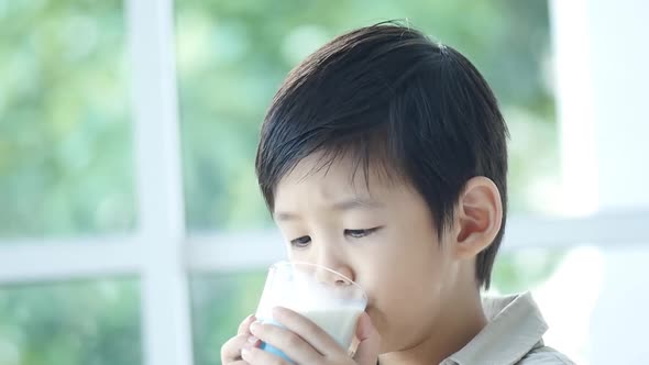 Cute Asian child drinking milk from a glass