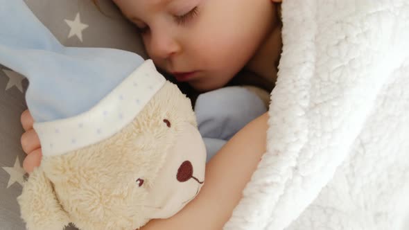 Close-up of a cute sleeping beautiful girl on a pillow with a bear