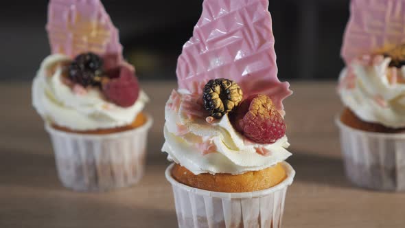 Cupcakes with Cream, Waffles and Fresh Berries in Paper Cups on the Table.