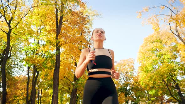  Video From Low Point of View on Young Beautiful Woman Running at Autumn Park on Bright Sunny Day