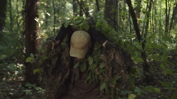 Military Sniper in Camouflage Getting Ready to Shoot in Forest at Dawn