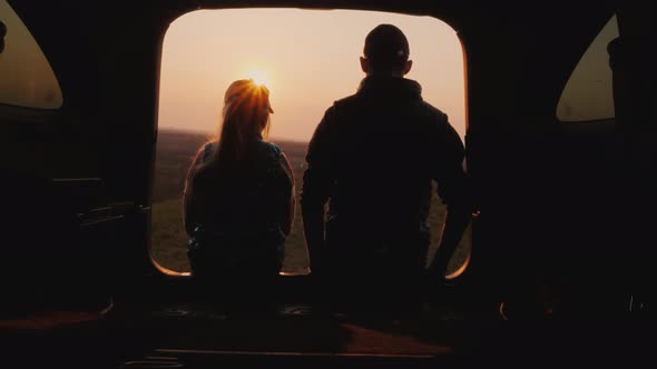 Brother and Sister Sit Side By Side in the Trunk of the Car Watching the Sunset in a Beautiful Place