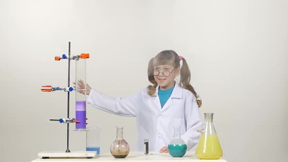 Little Girl Chemist with Two Ponytails in Uniform, Protective Glasses Has Successfully Tested