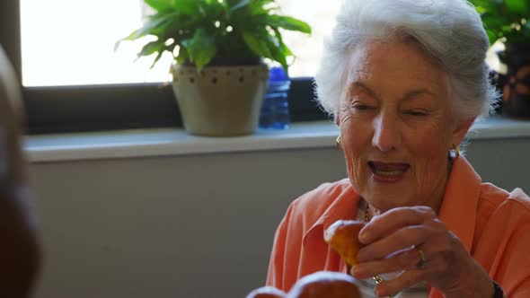 Senior woman taking cupcake from tray 4k