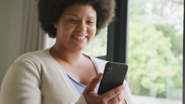 Video of happy plus size african american woman using smartphone
