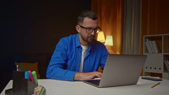 Frustrated Upset Man Sits at His Desk with Laptop and Shakes His Head Negatively