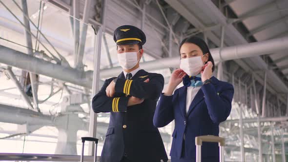 Airliner pilot and air hostess wear mask walking in airport terminal to the airplane during Covid19.