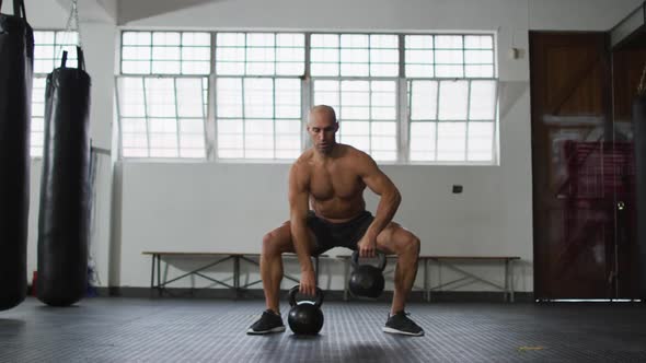 Fit caucasian man working out with kettle bells at the gym