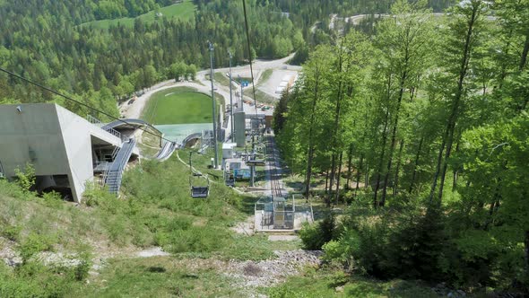 Riding a chair lift down the hill at Planica, Slovenia in the summertime with trees and ski jumps in