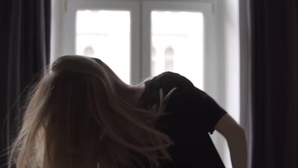 Relaxed Woman Dances Against the Background of the Large Windows of Her Apartment in the Morning