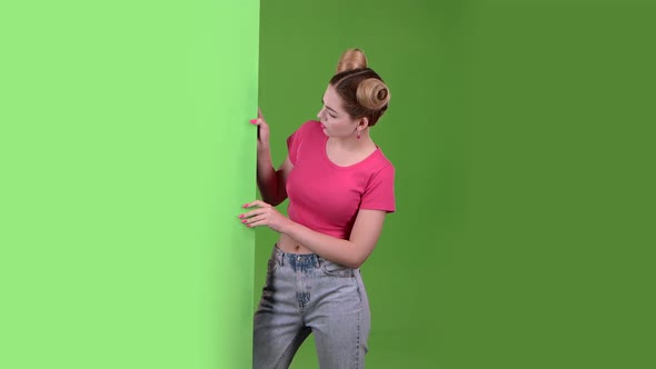 Teen Peeks Out From Behind a Green Board and Shows a Thumbs Down. Green Screen. Slow Motion