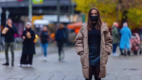 Time lapse of young woman wearing face mask and standing in city street, looking at camera alone