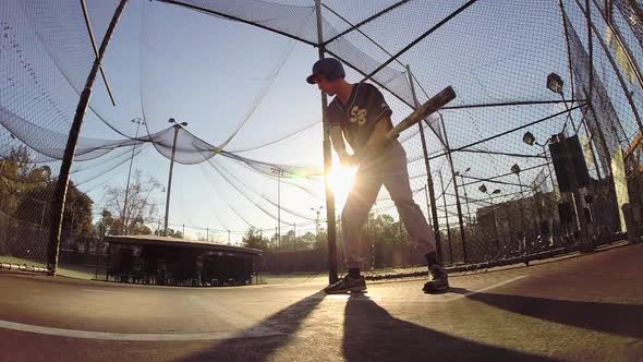 A baseball player practicing at the batting cages.