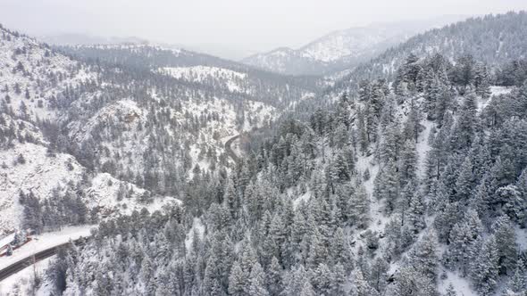 Aerial reveal left of Boulder Canyon Drive in Colorado during the winter as cars drive down icy road