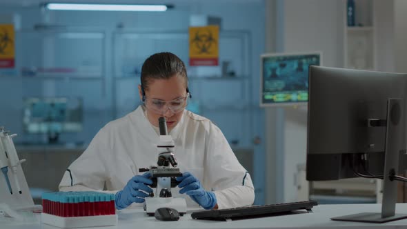 Lab Worker Using Magnifying Glass on Microscope