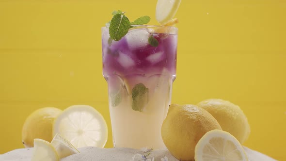 Pieces of Lime Fall Into a Glass of Refreshing Summer Lemonade Cocktail