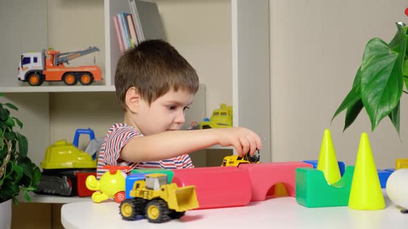 A Boy of 4 Years Old Plays with Toys Sitting at the Table