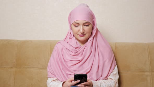 Young Woman in Hijab Smiling Typing on the Phone