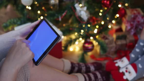 Woman in Christmas Warm Socks Sitting Under Decorated Fir Tree Tablet Chromakey