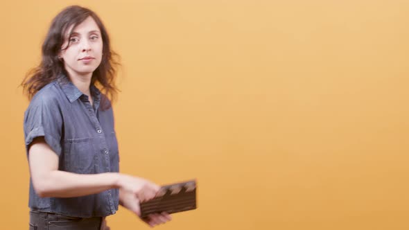 Young Female Using a Clapperboard Over Yellow Background