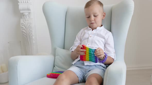 Portrait blonde boy with pop it sensory toy different forms.