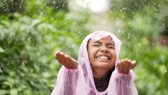 Happy girl wears raincoat and puts her hand