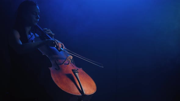 Young Beautiful Woman Playing a Melody on Cello. Smoky Dark Studio