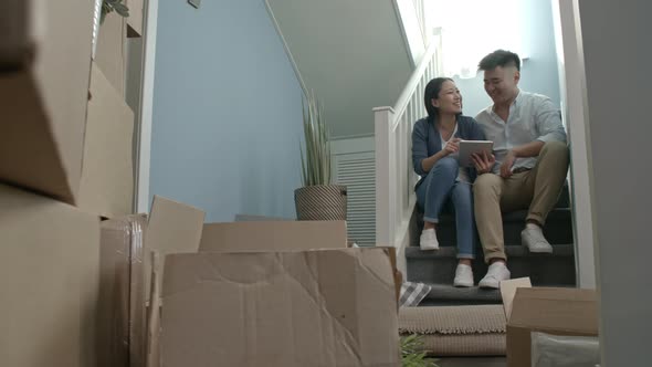 Couple with Tablet Sitting on Staircase in New House