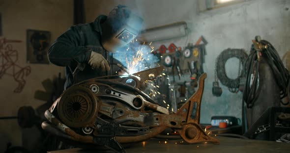 Locksmith Welds the Decorative Metal Steampunk Fish Sculpture with a Lot of Sparks and Flashes in