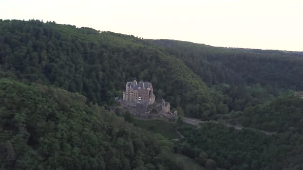 Eltz Castle or Burg Eltz in Germany surrounded by woods. Aerial backward ascendent