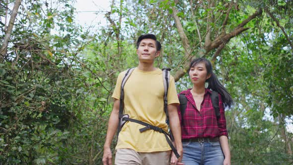 Young Asian man and woman friend couple backpacker traveling in the forest together during summer.