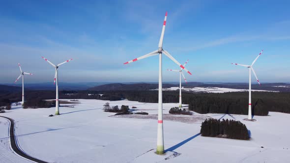 Flying towards a windfarm. Aerial view of wind turbines on a snowy field in Germany.