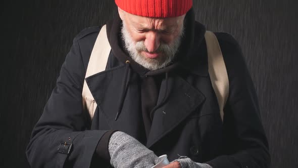 Portrait of Homeless Beggar in the Rain Counting Change Lying in Cup for Money