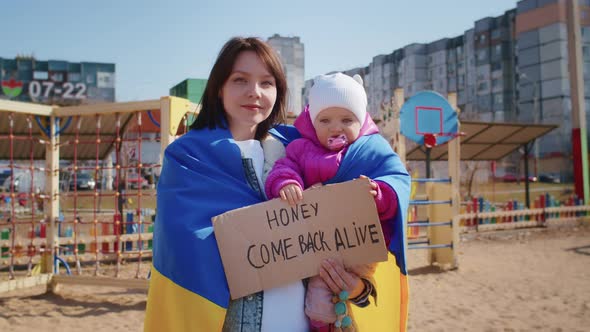 Portrait of a Joyful Ukrainian Woman Holding a Child and a Ukrainian Flag