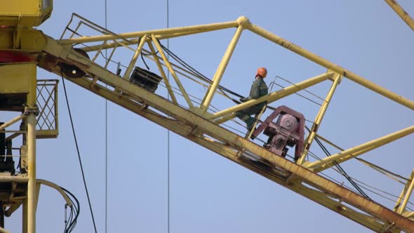 Construction Worker Builder Sits on the Yellow Crane