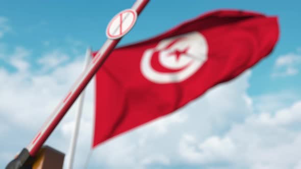 Closing Barrier with STOP CORONAVIRUS Sign at the Tunisian Flag