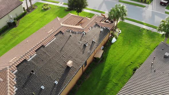 Rotating aerial of a pricey roof tile repair over an impossibly green grass in South Florida