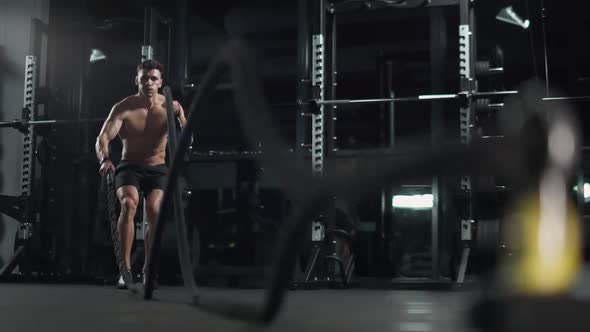 Athletic Man Performs Exercises with Battle Ropes Endurance Training in the Gym  Slow Motion