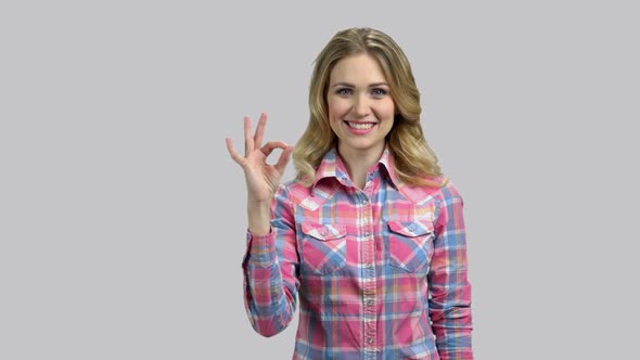 Happy Young Woman with Blond Hair Shows Okay Gesture