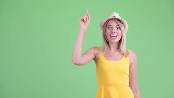 Happy Young Blonde Tourist Woman Pointing Up and Looking Excited