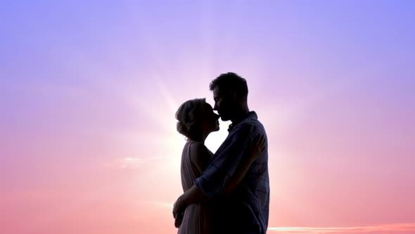 Couple in Love Embracing Heartily Against Shiny Sunrise, Tender Feelings, Kisses