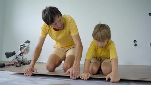 Father and His Little Son Install Laminate on the Floor in Their Apartment