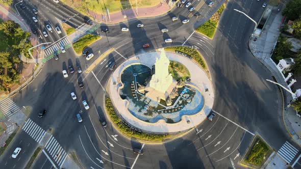 High angle aerial orbiting around a roundabout and the Monument of the Spanish at golden hour