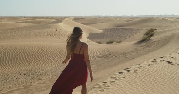 Beautiful Woman in Red Dress is Walking on Sand Wearing Red Dress