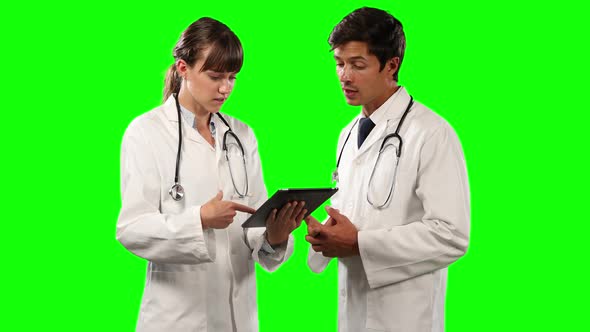 Side view of doctors discussing and holding a digital tablet with green screen