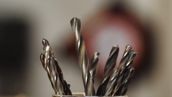 Close Up of Several Drills Standing in Stand Builder's Hand in Nylon Glove Takes One Drill